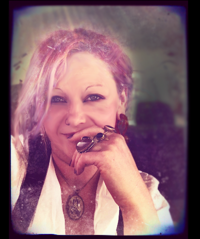 A close-up portrait of Cerid with a soft, ethereal glow and a vintage film border. She is smiling gently with her hand resting against her chin, showcasing several large, ornate rings. She has pink-toned hair and is wearing a white collared shirt, a dark vest, and a large oval pendant necklace.
