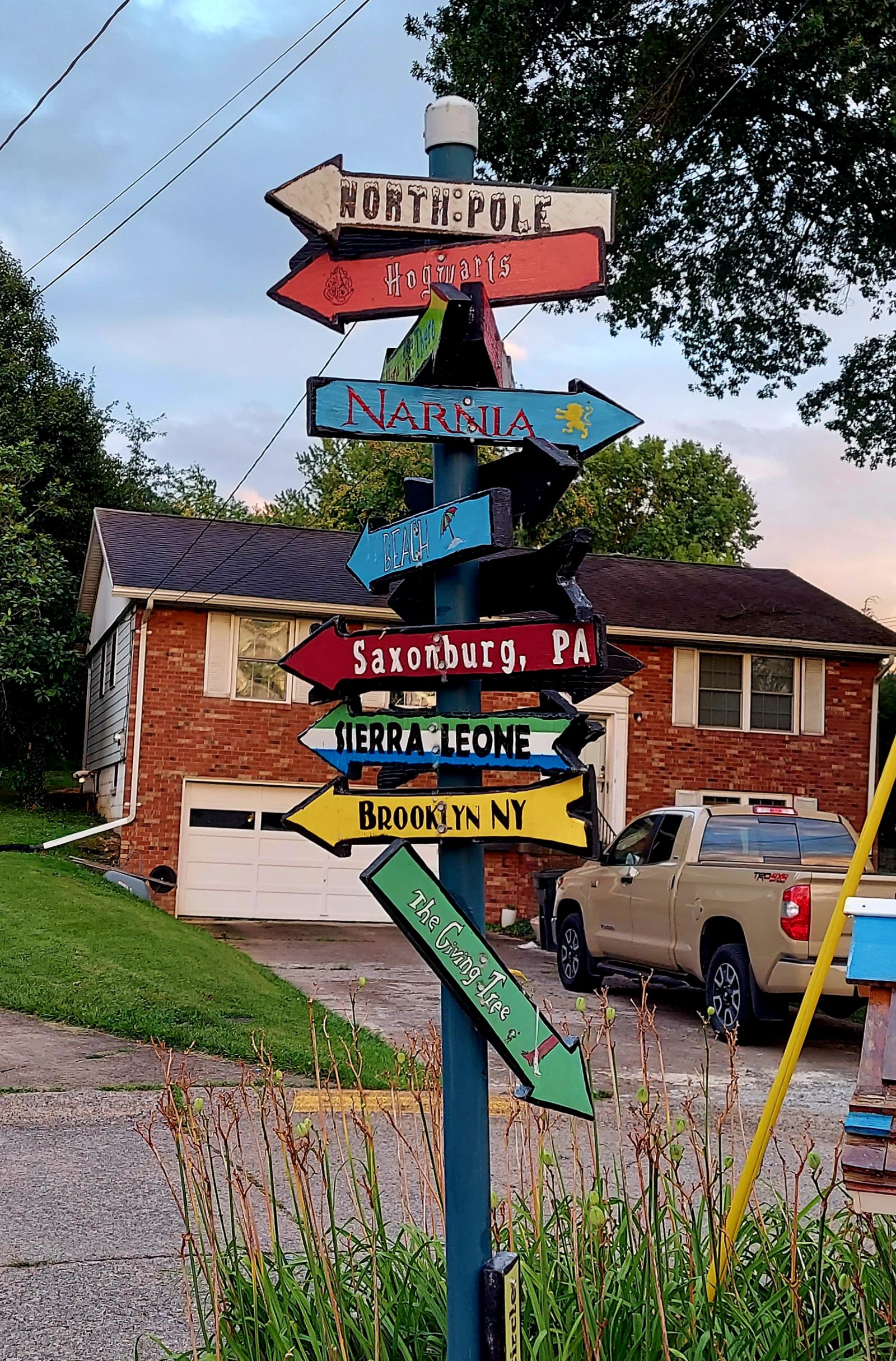 Whimsical signs in a neighborhood pointing in random directions with places like "North Pole" and "Narnia."