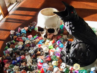 DnD dice with a Raven Dice roller and a Halloween skull candle holder in evening sunlight. 